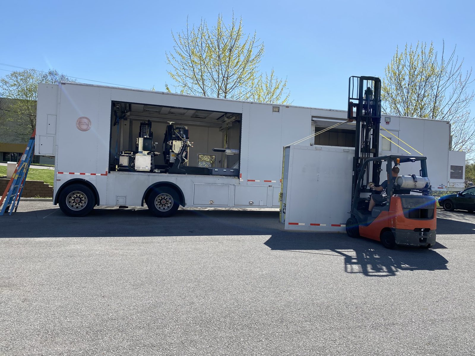 Mobile coach mid-rebuild with imaging system being installed by forklift